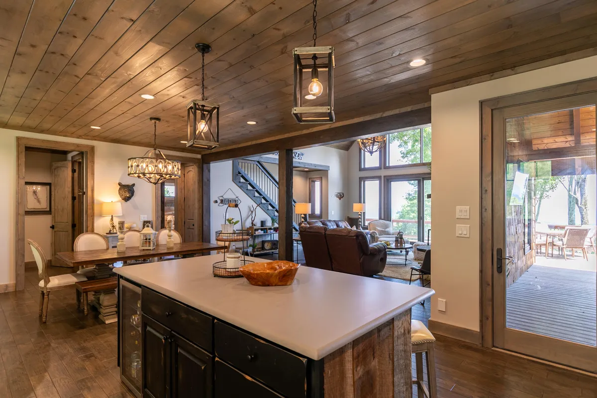 An open-plan layout showcasing the kitchen island, dining table, comfortable living area, and expansive windows letting in natural light. The space feels cozy yet spacious, ideal for meals, conversations, and relaxation.