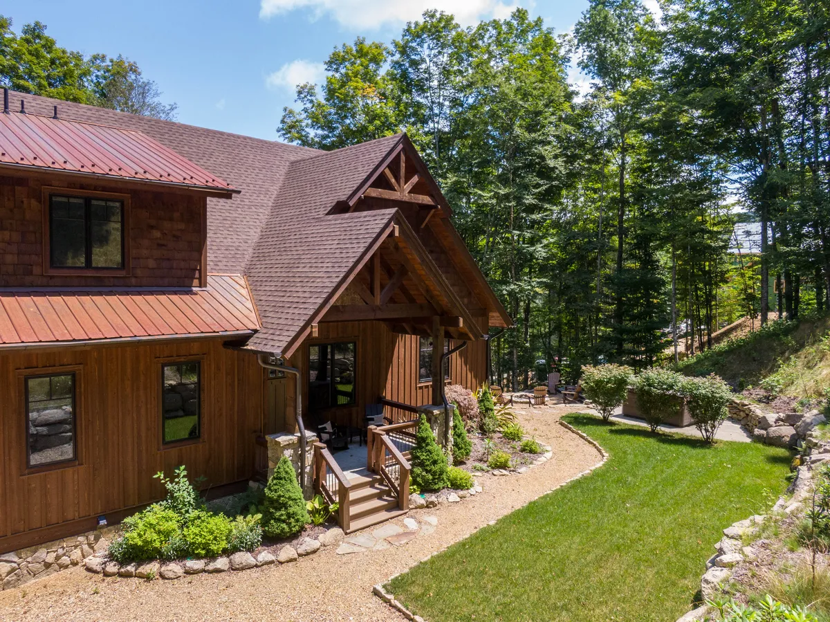 A beautiful exterior view of the property featuring warm wooden architecture, a landscaped garden, and an inviting outdoor seating area. The space seamlessly connects the home to its natural surroundings, perfect for gatherings and quiet moments alike.